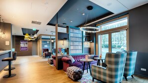 A modern library with a sofa, chairs, and a table. - Premier Inn Wiesbaden City Centre (Wiesbaden)