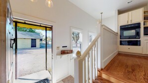 Una cocina moderna con armarios blancos, una escalera de madera y vistas al exterior.