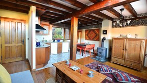A spacious kitchen with wooden beams, a dining area with a table and chairs, and a traditional stove.