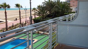 A pool area with a view of the beach and palm trees.