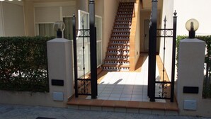 A staircase leading to a gated entrance with a tiled floor and a metal gate with decorative elements.