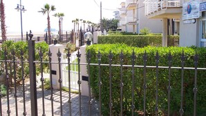 A coastal hotel with a gated entrance, palm trees, and a view of the beach.