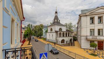 Une vue de rue avec un panneau indiquant un passage piéton, une église dotée d’un clocher imposant et des immeubles avec des balcons.