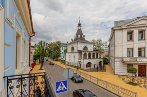 Vista de una calle con un paso de peatones, una iglesia con una aguja alta y edificios con balcones.