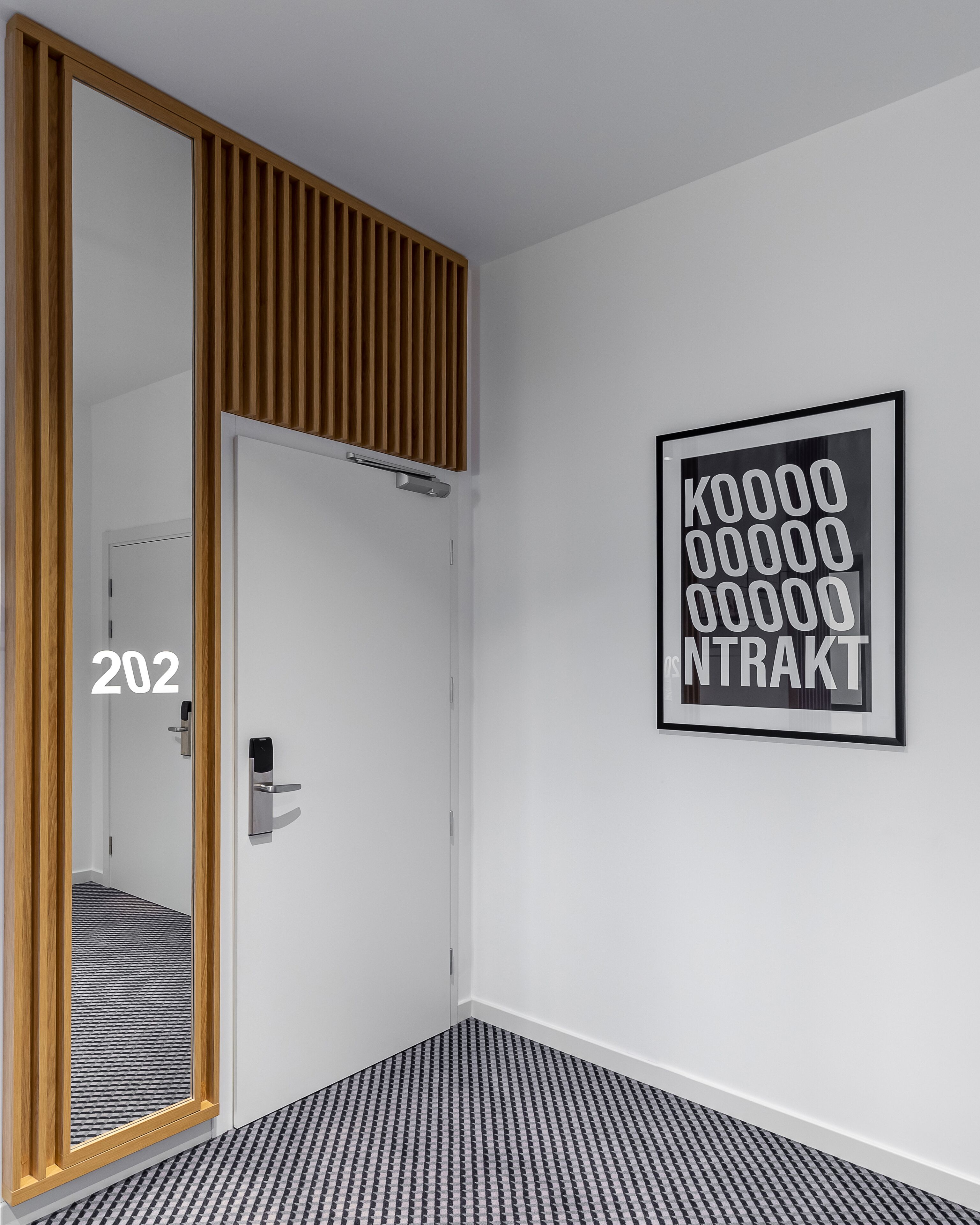 Ein moderner Raum mit Holztür, einem gerahmten Schild an der Wand und einem gemusterten Boden.
