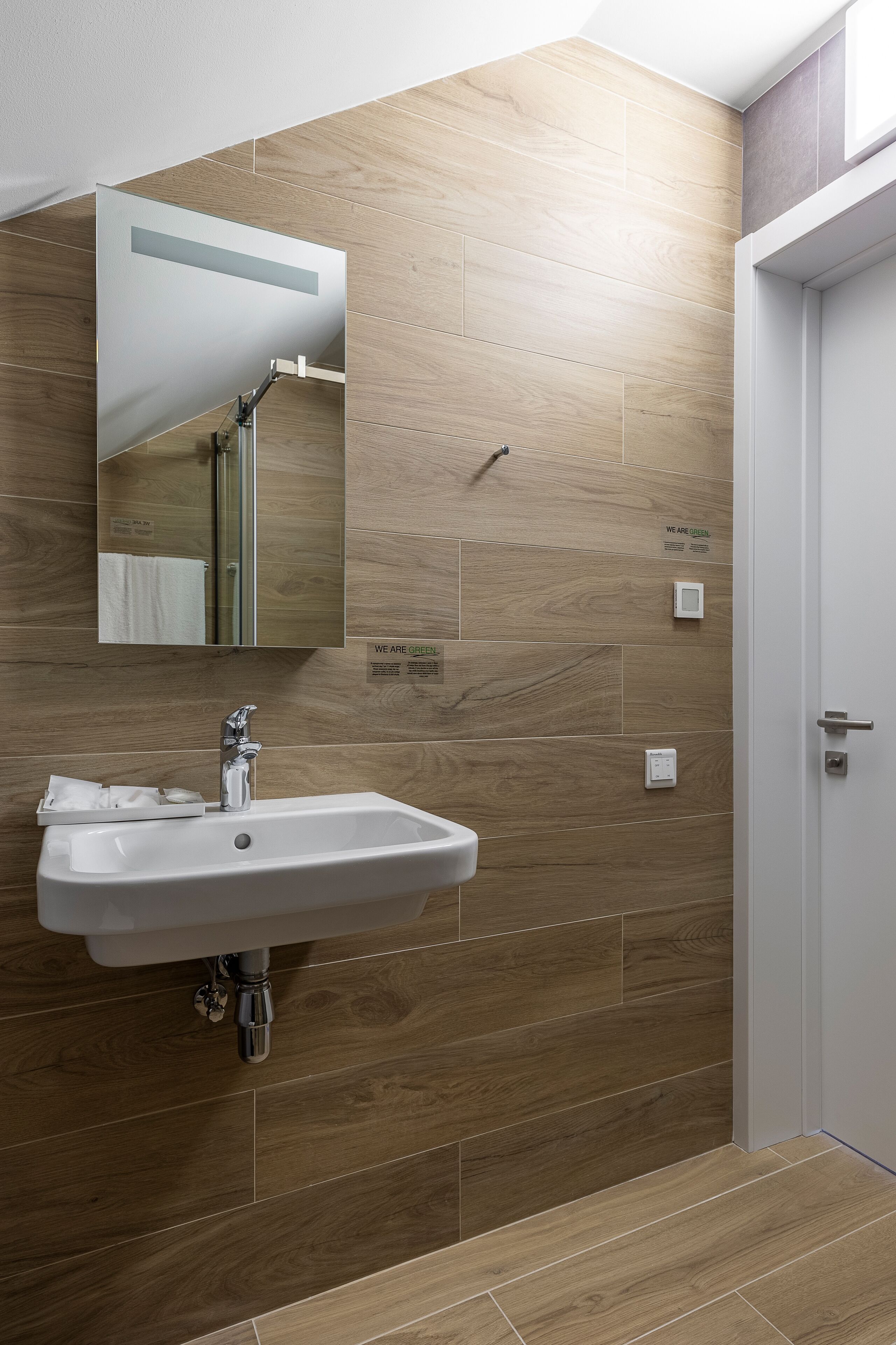 A modern bathroom with a sink, mirror, and wooden wall tiles.