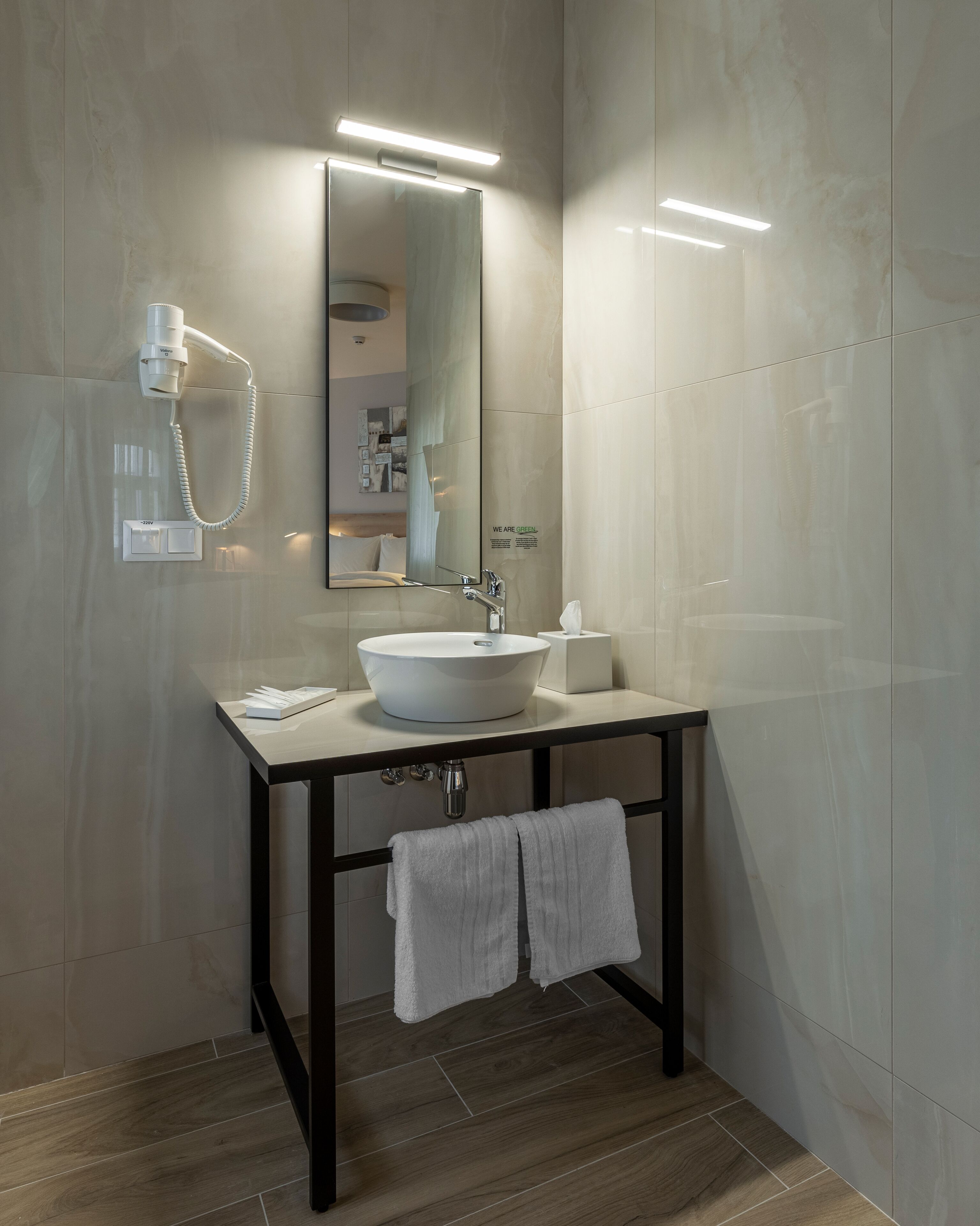 A modern bathroom with a white sink, a mirror, and a towel rack.