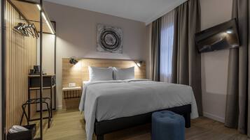 Et moderne hotelværelse med seng, fjernsyn, skrivebord og stol.