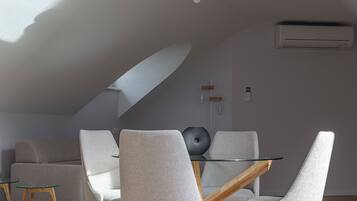 A modern dining area with a glass table, grey upholstered chairs, and wooden legs.