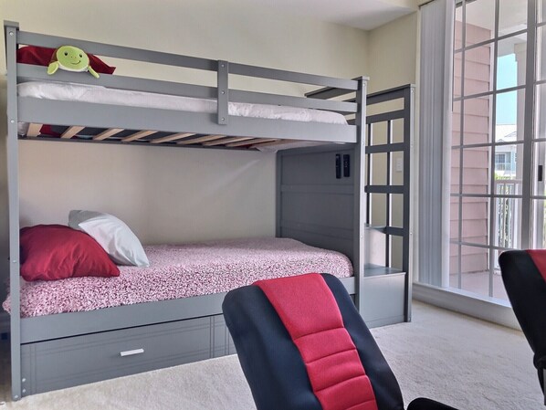 A bunk bed with a red and white pillow, a small turtle decoration, and a window with a view of the outside.
