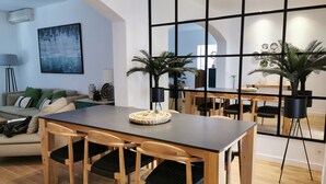 Un espace repas moderne avec une table et des chaises en bois, un grand miroir et des plantes en pot.