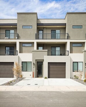 A modern multi-story residential building with a flat roof, large windows, and a clean, minimalist design. - Large Home Sleeps 16-Pool Perfect For Family Fun! (St. George)