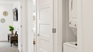 A hallway with white doors, a small table with a plant, and a washing machine. - Large Home Sleeps 16-Pool Perfect For Family Fun! (St. George)