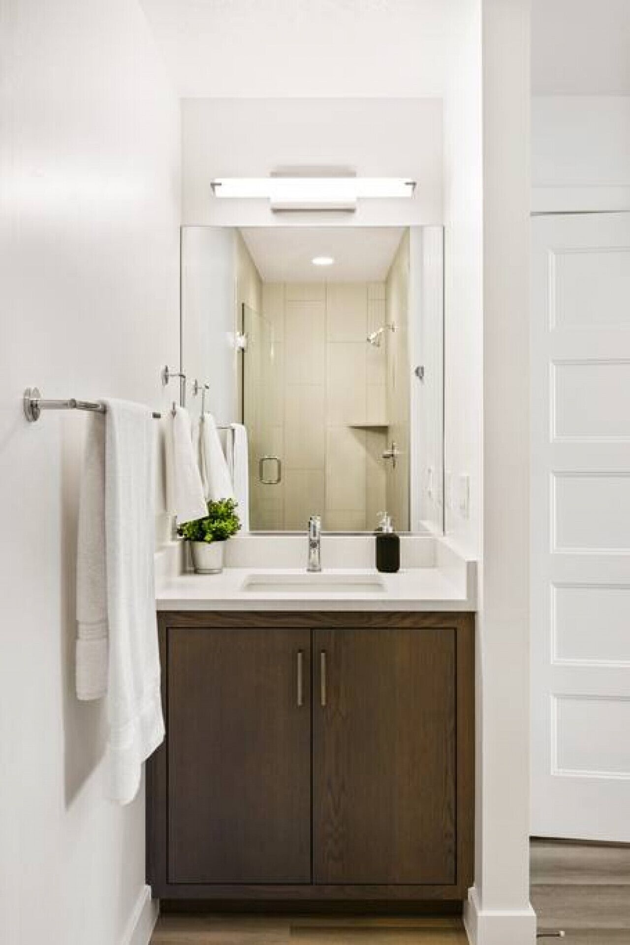 Un baño moderno con un espejo grande, un lavabo y armarios de madera oscura.