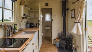 A compact kitchen with wooden cabinets, a sink, and a stove. - Rumwold by Bloom Stays -  a rural shepherds hut sleeping 2 with amazing views! (Ashford)