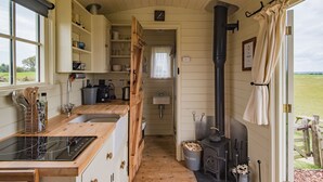 Una cucina compatta con mobili in legno, un piano cottura integrato e una finestra che si affaccia su una zona verde.