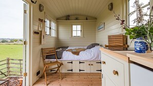 Una camera accogliente con un letto, una sedia, una scrivania in legno e una finestra vista sulla campagna.