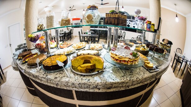 A buffet with various dishes and a glass display case. - Hotel Tito's (Capanema)