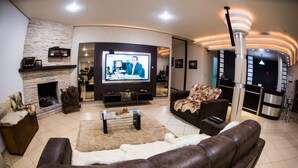 A modern living room with a fireplace, a flat-screen TV, leather sofas, and a coffee table. - Hotel Tito's (Capanema)