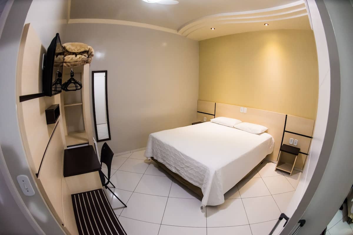 A modern hotel room with a large bed, a desk, and a chair.