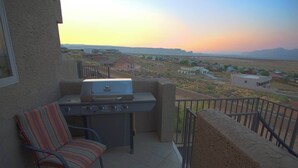 Un balcón con una parrilla, una silla y vistas a un paisaje desértico.
