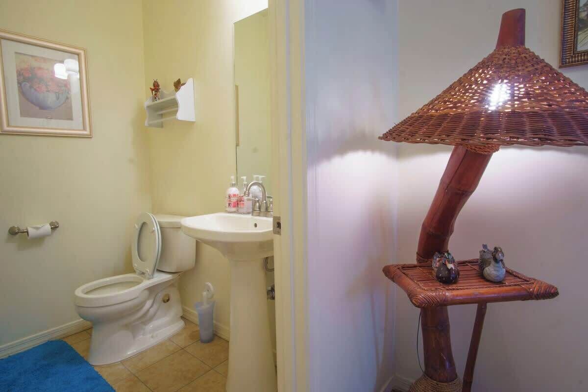 A bathroom with a toilet, sink, mirror, and a decorative lamp.