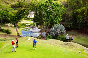 A golf course with a gazebo, pond, and lush greenery.