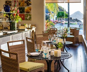 A restaurant with wicker chairs and tables, a bar area, and a view of the sea.