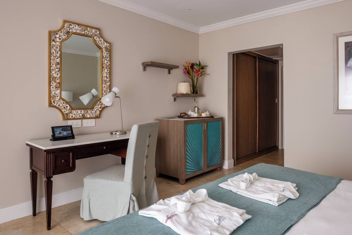 A hotel room with a desk, chair, wardrobe, and a bed with towels.