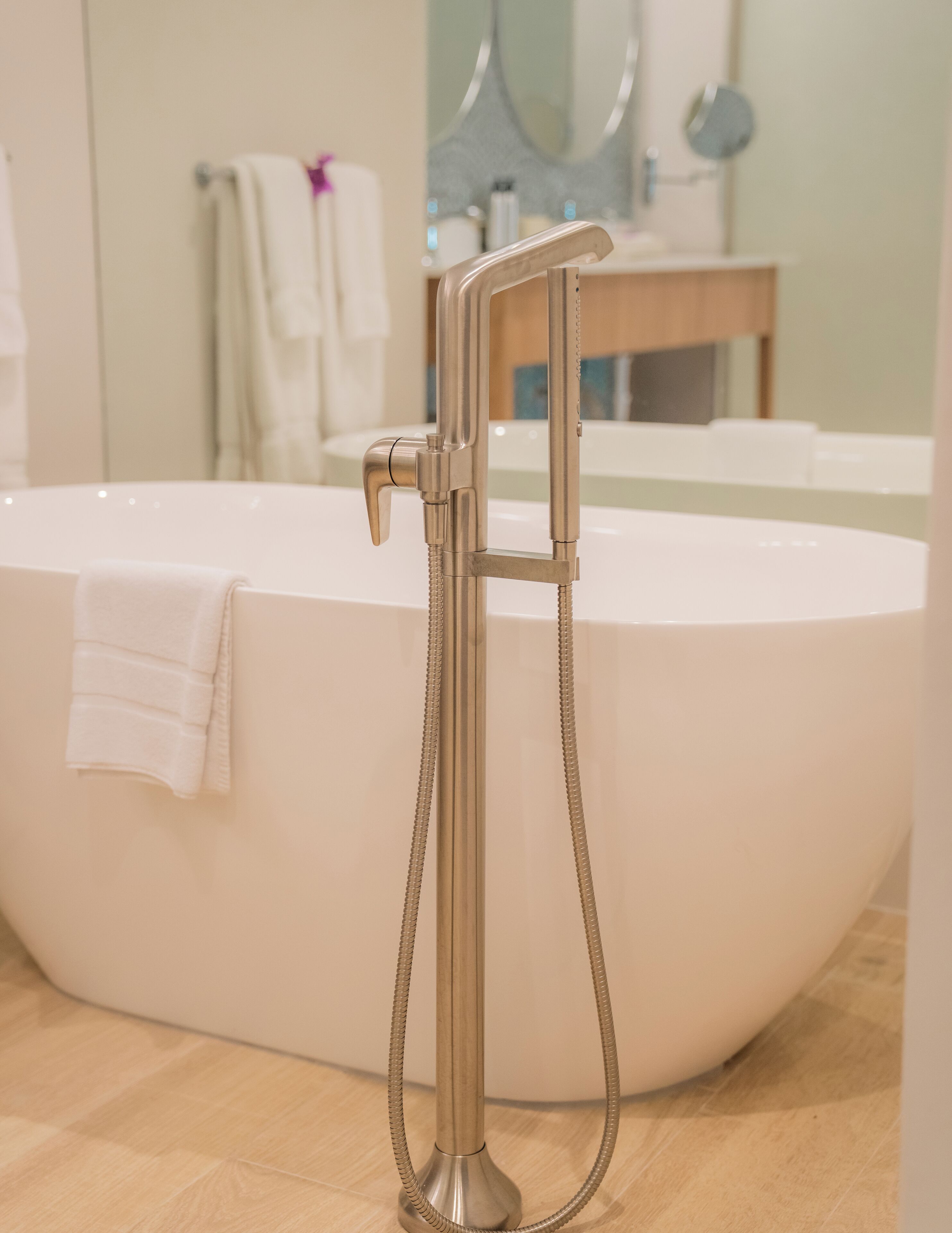 Een moderne badkamer met een vrijstaand bad, een handdouche en een handdoekrek.