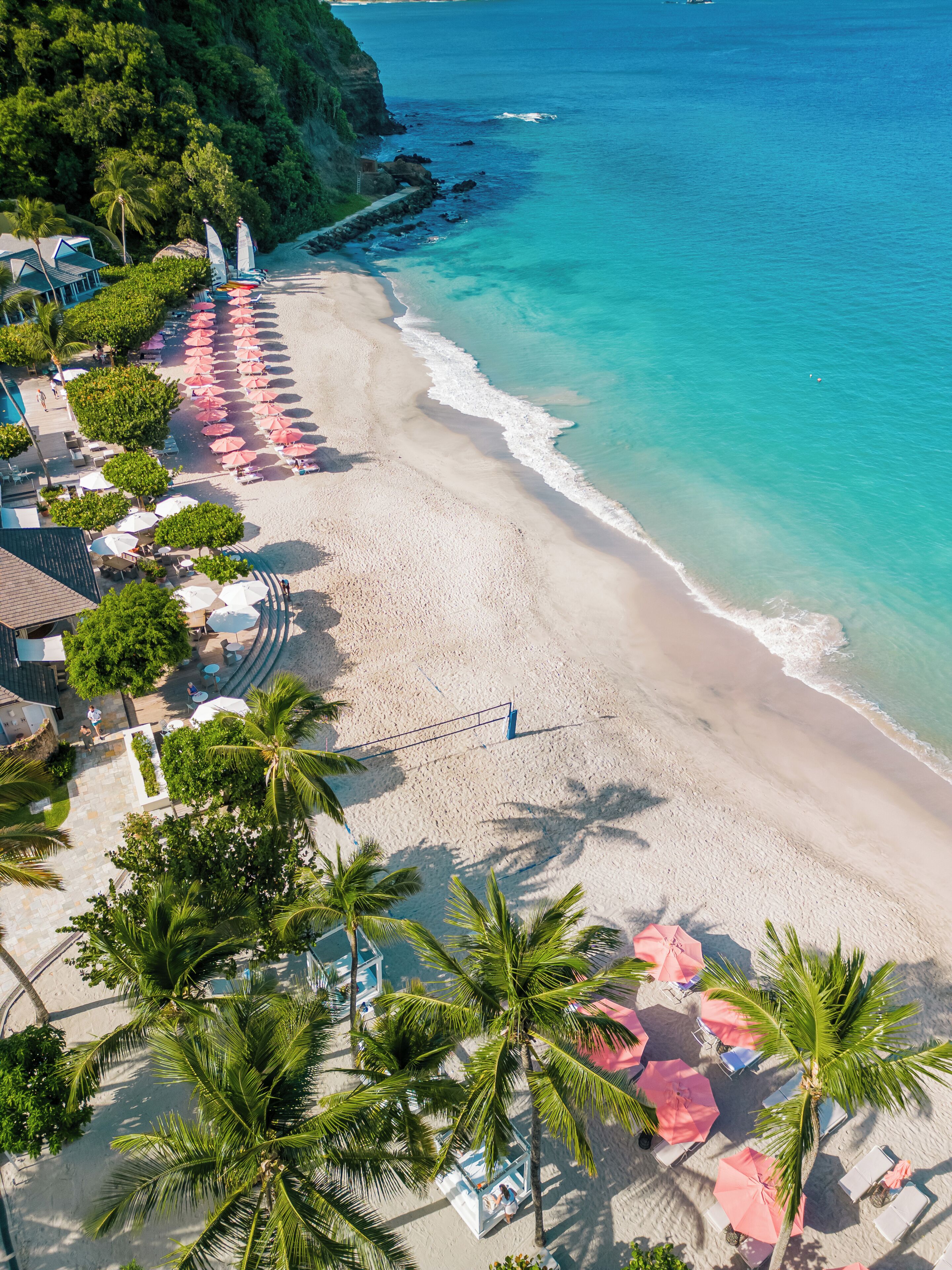 A beach resort with a pool area, lounge chairs, and umbrellas.