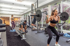 A gym with various exercise equipment, including treadmills, weight machines, and free weights.