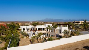 Eine moderne Villa mit Pool, umgeben von Palmen und einer Wüstenlandschaft.