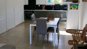Eine moderne Küche mit Essbereich, mit einem weißen Tisch, Stühlen und einem kleinen Holztisch mit Fernbedienung.