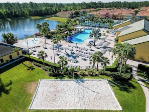 A resort with a large pool, sun loungers, and a sandy area.