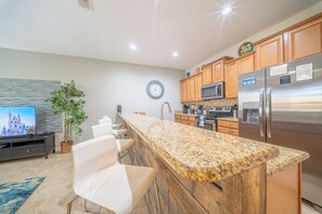 A modern kitchen with a granite countertop, stainless steel appliances, and wooden cabinets. - Near Disney, Private Pool, No Rear Neighbors & Front-Door Parking, Gated Resort (Kissimmee)