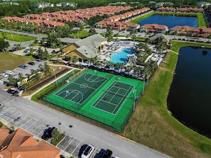 Vista aérea de um bairro residencial com quadra de tênis, piscina e um lago.