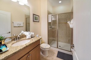 A bathroom with two sinks, a toilet, and a glass-enclosed shower.