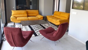 Una sala de estar moderna con dos sofás amarillos, una mesa de centro de vidrio y dos sillones rojos.