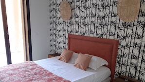 Un dormitorio con cama, dos mesitas de noche, cabecera roja y papel tapiz de bambú.