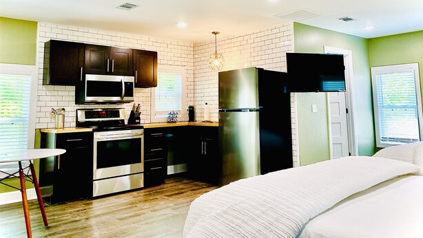 A compact kitchen with dark cabinets, a stainless steel microwave, and a refrigerator.