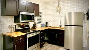 A modern kitchen with dark cabinets, stainless steel appliances, and a white brick backsplash.