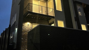 A multi-story building with a balcony on the second floor, a brick facade, and a staircase leading to the entrance. - Gorgeous modern Denver townhome close to city center (Denver)