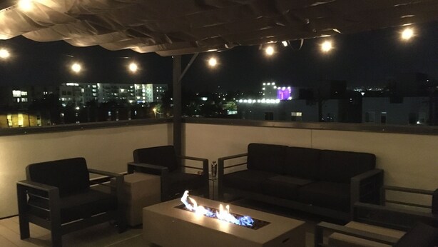 A rooftop terrace with a fire feature, seating, and a view of the cityscape at night. - Gorgeous modern Denver townhome close to city center (Denver)