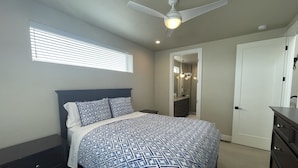 A bedroom with a bed, a dresser, a ceiling fan, and a bathroom visible through an open door. - Gorgeous modern Denver townhome close to city center (Denver)