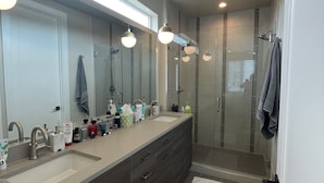 A modern bathroom with a large mirror, dual sinks, and a walk-in shower. - Gorgeous modern Denver townhome close to city center (Denver)