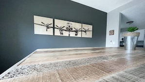 Un espace repas avec une longue table en bois et une œuvre d’art représentant trois avions, accrochée au mur.