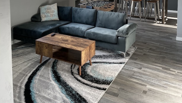 Un salon moderne avec un canapé d’angle, une table basse en bois et une table de baby-foot.
