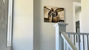 Un escalier avec des rampes blanches mène à un palier. On peut voir un luminaire au plafond au-dessus du palier.