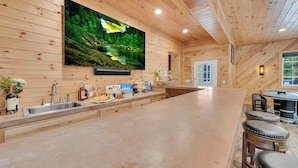 Una cocina moderna con una isla grande, paredes de madera y un televisor de pantalla plana montado sobre la isla.